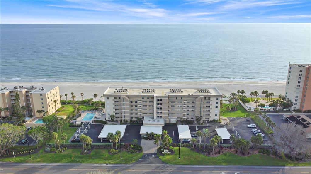 An aerial view shows a multi-story beachfront condominium building with a pool and parking lot — 4325 GULF OF MEXICO DRIVE UNIT 305, LONGBOAT KEY, FL