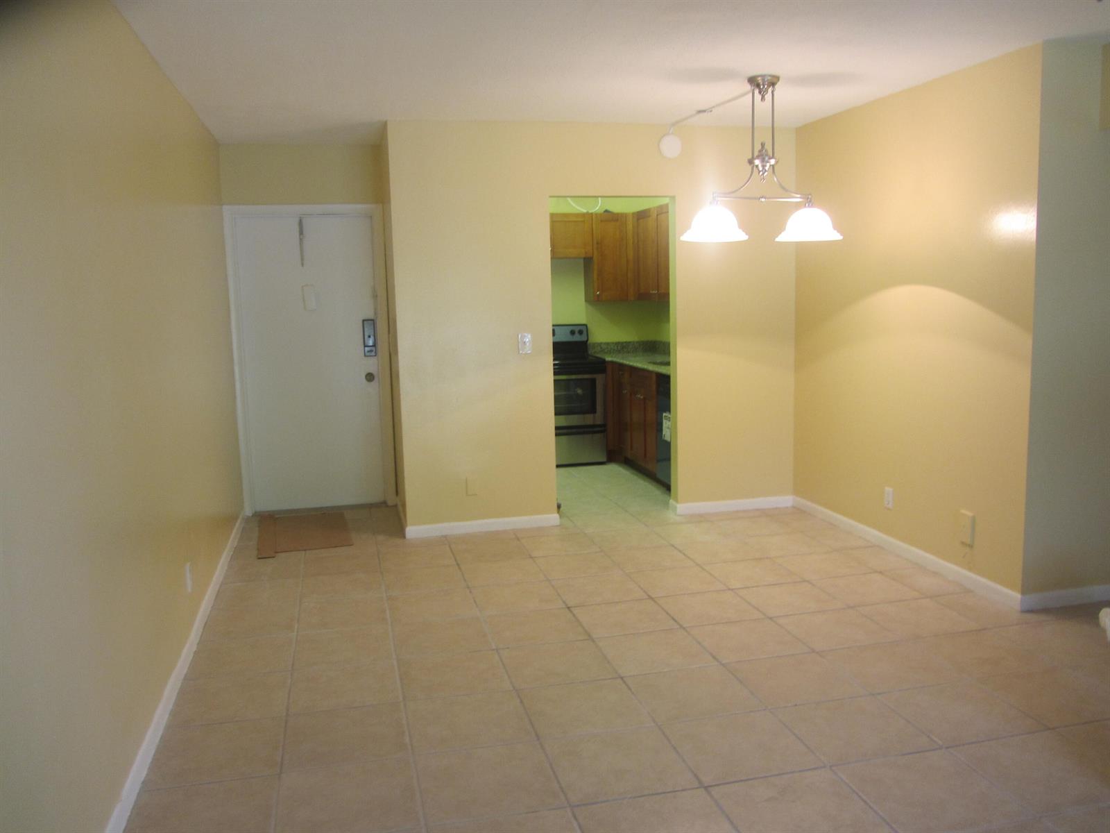 A dining area with tile floors and a pendant light leads into a small kitchen — 626 NW 13th Street # 0280, Boca Raton FL 33486, BOCA RATON, FL
