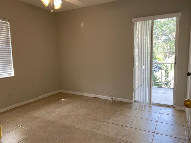 An empty room features beige walls, light-colored tile flooring, a window, and a sliding glass door — 626 NW 13th Street # 0280, Boca Raton FL 33486, BOCA RATON, FL