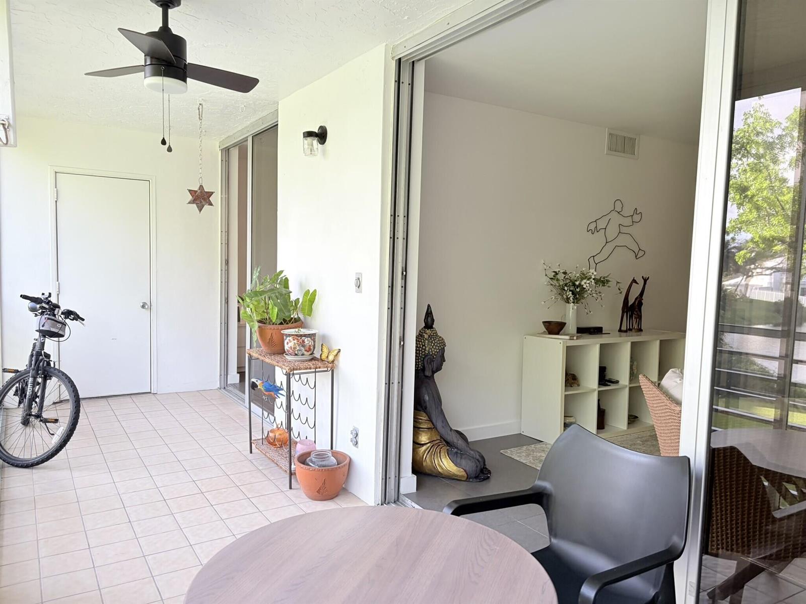 A covered patio with a ceiling fan, a bicycle, and a sliding door to an interior — 3503 Oaks Way # 202, Pompano Beach FL 33069, POMPANO BEACH, FL