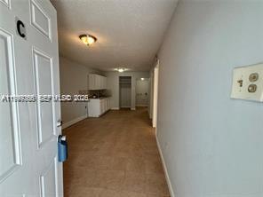 A view from an open doorway looking into a carpeted apartment interior with a kitchen — 820 21st St # C, West Palm Beach FL 33407, WEST PALM BEACH, FL