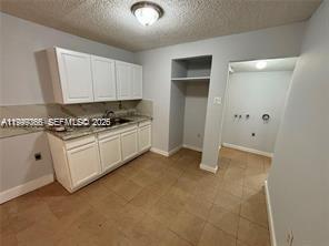 A kitchen with white cabinets, a sink, and an adjacent laundry area with tile flooring — 820 21st St # C, West Palm Beach FL 33407, WEST PALM BEACH, FL
