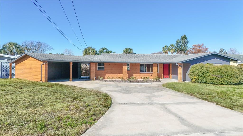 A single-story house with wood siding, a carport, and a concrete driveway under a clear sky — 1503 CANAL COURT, TAVARES, FL