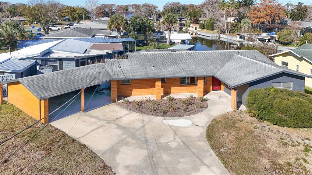 An aerial view of a single-story house with a wood-paneled facade and a carport — 1503 CANAL COURT, TAVARES, FL