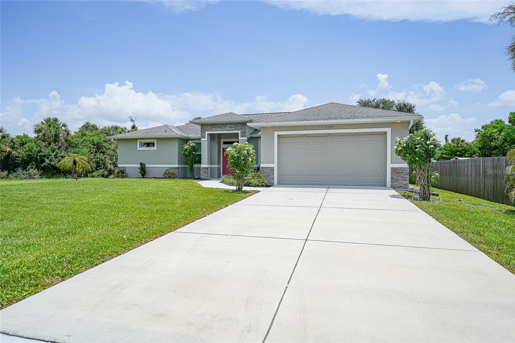A single-story house with a beige exterior, a two-car garage, and a concrete driveway — 1182 YORKSHIRE STREET, PORT CHARLOTTE, FL