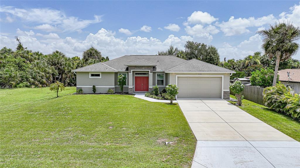 A single-story house with a beige exterior, red front door, and a two-car garage — 1182 YORKSHIRE STREET, PORT CHARLOTTE, FL