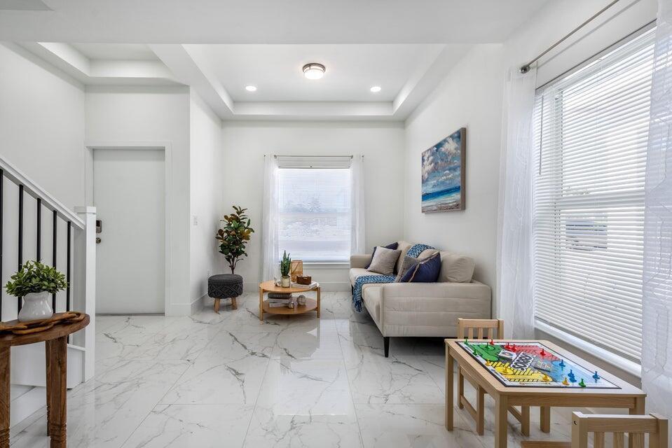 A bright living room features white marble floors, a beige sofa, and a game table — 432 NW 13th Avenue, Boynton Beach FL 33435, BOYNTON BEACH, FL