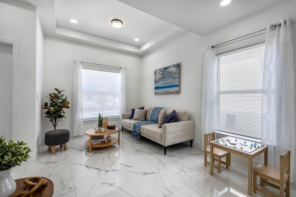 A bright living room features white marble floors, a beige sofa, and a small play table — 432 NW 13th Avenue, Boynton Beach FL 33435, BOYNTON BEACH, FL