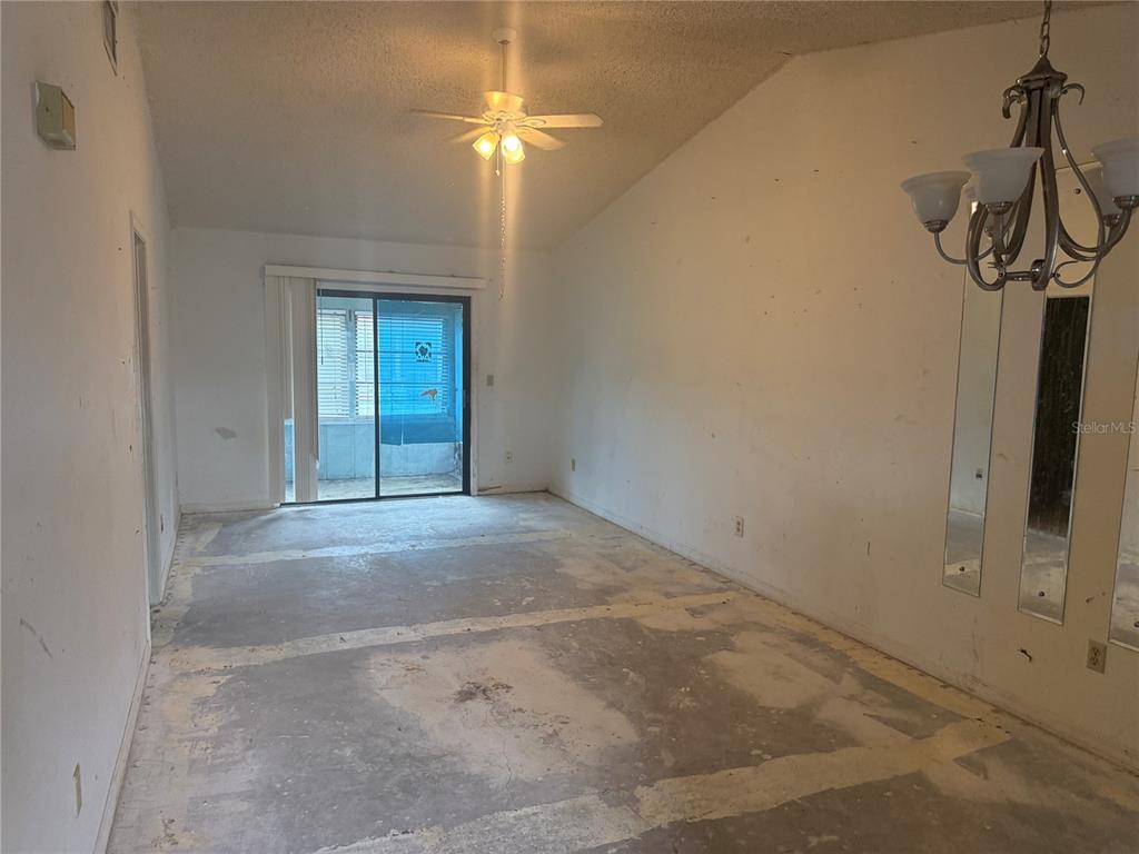An empty room with a vaulted ceiling, a ceiling fan, and exposed concrete flooring — 1116 FAIRVILLA DRIVE UNIT 1116, NEW SMYRNA BEACH, FL