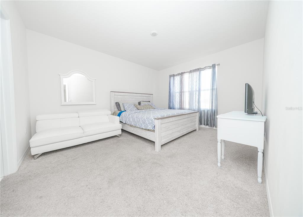 A bedroom features a white bed, a white sofa, and a white desk on carpet — 3838 WHITNEY WAY, HAINES CITY, FL