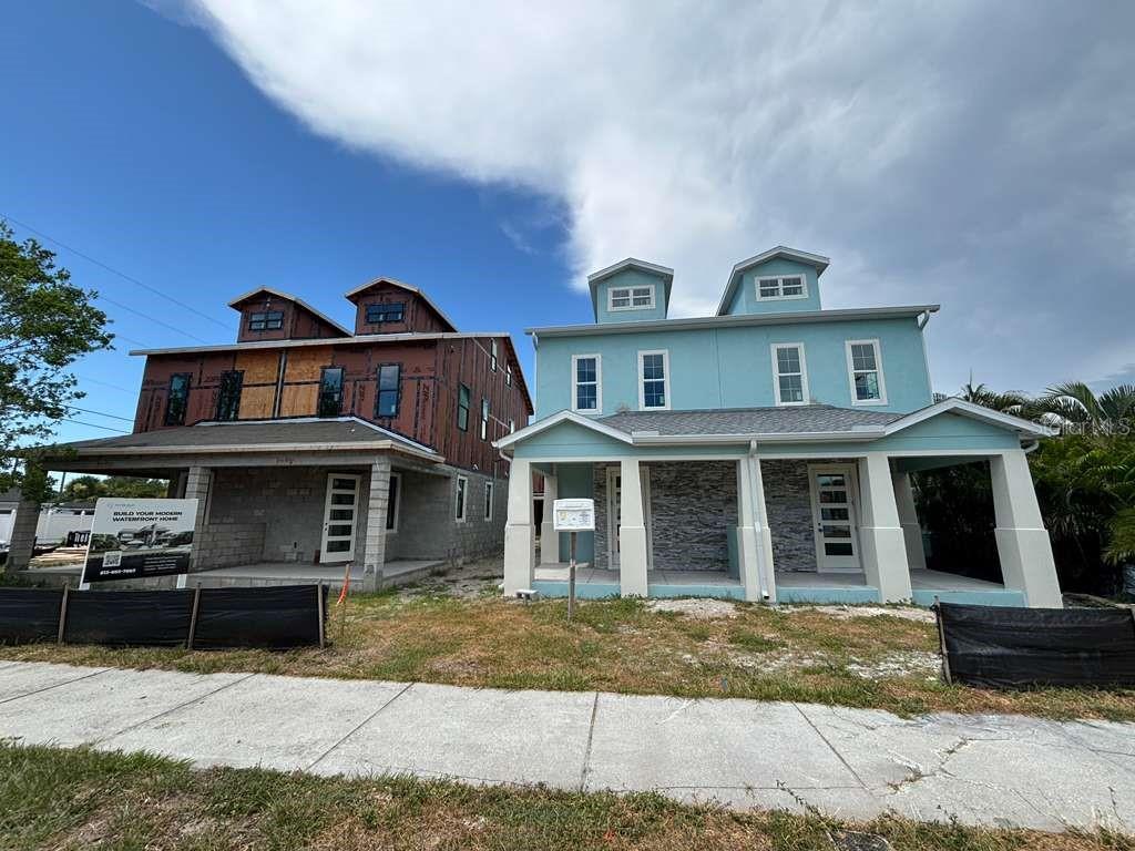 Two multi-story houses stand side-by-side, one under construction and the other with a finished exterior — 6179 1ST AVENUE N, ST PETERSBURG, FL
