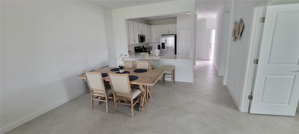A dining area with a wooden table and chairs sits adjacent to an open-concept kitchen — 8716 SAINT KITTS CIRCLE, ENGLEWOOD, FL