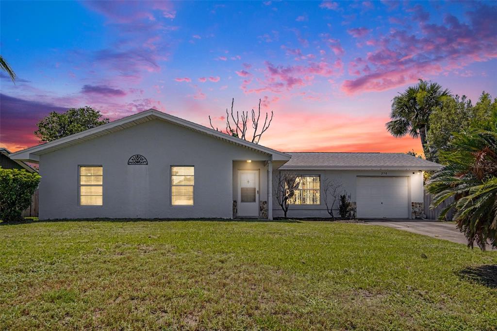 A single-story house with a gray exterior, a front-facing garage, and a sunset sky — 250 CAMBRIDGE AVENUE NE, PALM BAY, FL