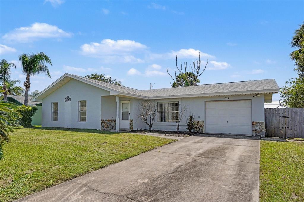 A single-story house with a light-colored exterior, a concrete driveway, and a one-car garage — 250 CAMBRIDGE AVENUE NE, PALM BAY, FL