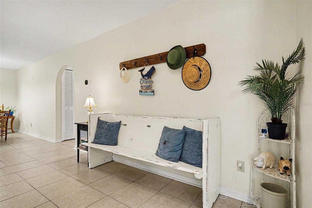 A white wooden bench sits against a wall with a coat rack and hats — 250 CAMBRIDGE AVENUE NE, PALM BAY, FL