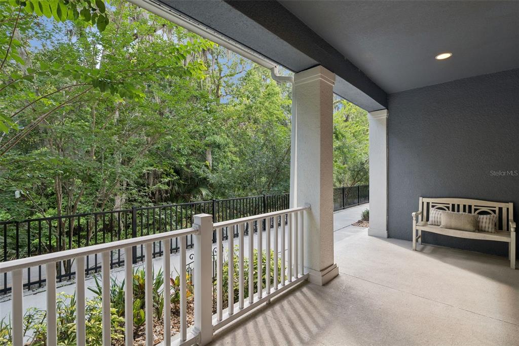 A covered patio features a white wooden bench, a white railing, and a wooded view — 1320 SPOTTED SANDPIPER LOOP, WINTER SPRINGS, FL