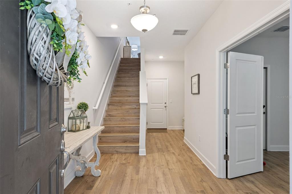 An entryway features wood-look flooring, a staircase, a console table, and white interior doors — 1320 SPOTTED SANDPIPER LOOP, WINTER SPRINGS, FL