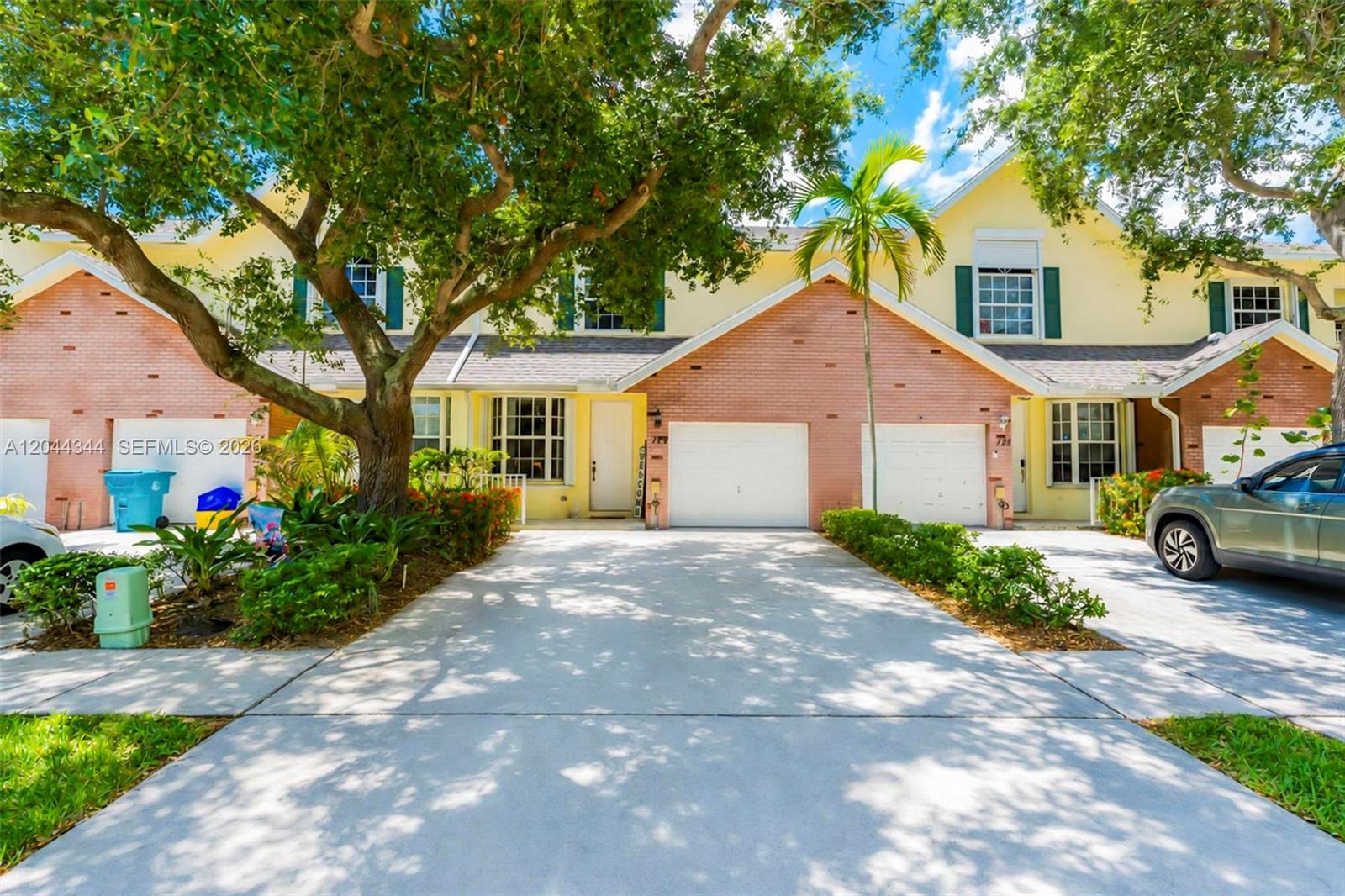 A two-story townhouse with a brick facade, a two-car garage, and a large shade tree — 126 Spruce St, Boynton Beach FL 33426, BOYNTON BEACH, FL
