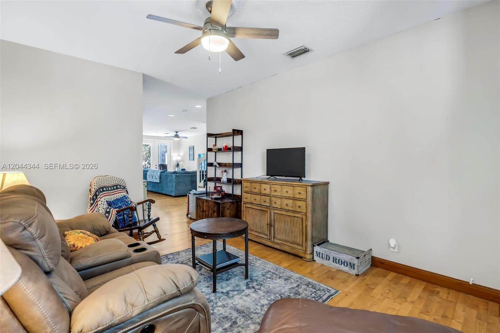 A living room features a brown leather sofa, wood flooring, and a television on a dresser — 126 Spruce St, Boynton Beach FL 33426, BOYNTON BEACH, FL
