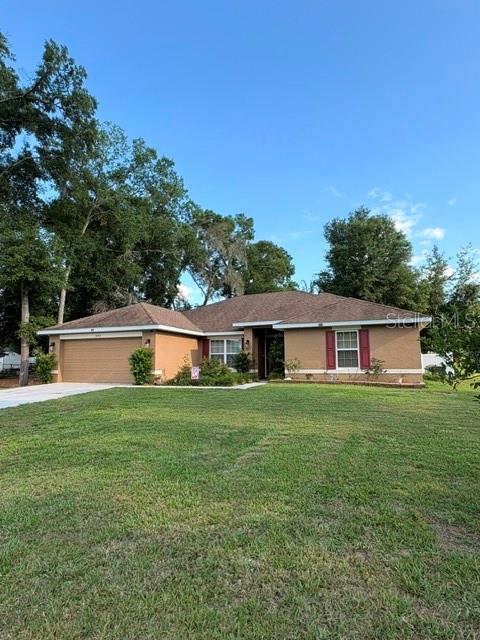 A single-story tan house with a brown shingled roof and a two-car garage — 8262 SE 158TH PLACE, SUMMERFIELD, FL