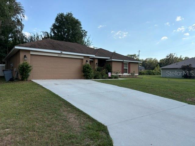 A single-story house with a tan exterior, a two-car garage, and a concrete driveway — 8262 SE 158TH PLACE, SUMMERFIELD, FL