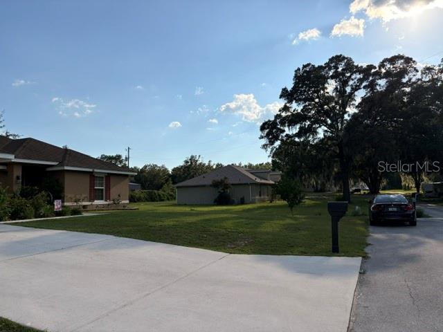 A view of two suburban houses with a large grassy yard and a parked car — 8262 SE 158TH PLACE, SUMMERFIELD, FL