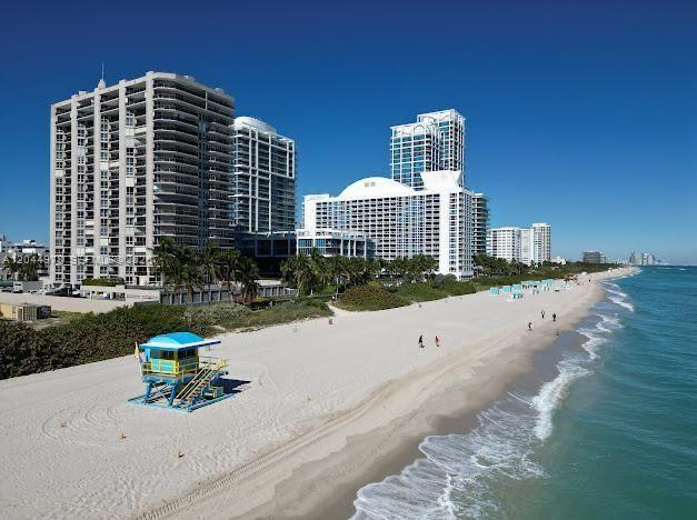 An aerial view of a sandy beach with a lifeguard tower and tall residential buildings — 6767 Collins Ave # 1608, Miami Beach FL 33141, MIAMI BEACH, FL