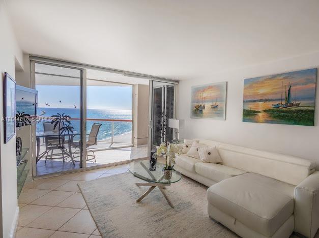 A living room with a white sectional sofa, glass coffee table, and sliding doors to a balcony — 6767 Collins Ave # 1608, Miami Beach FL 33141, MIAMI BEACH, FL