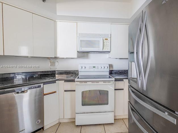 A kitchen features white cabinets, stainless steel appliances, and dark granite countertops — 6767 Collins Ave # 1608, Miami Beach FL 33141, MIAMI BEACH, FL