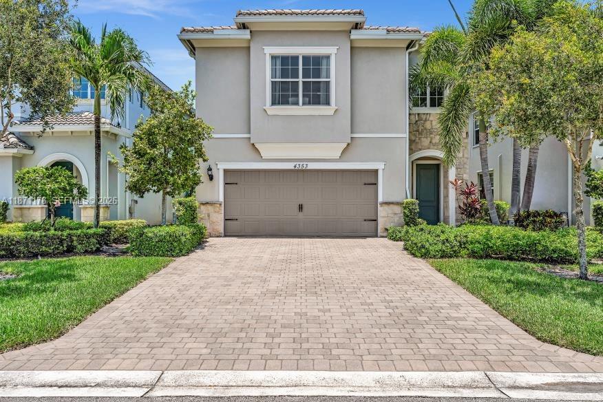 A two-story house with a beige stucco facade, stone accents, and a paved driveway — 4353 Large Leaf Ln, Hollywood FL 33021, HOLLYWOOD, FL
