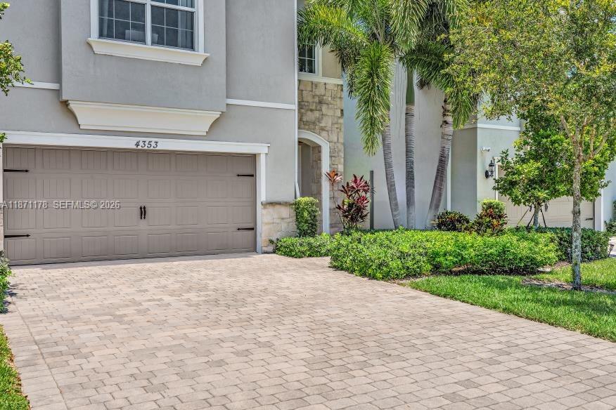 A beige house exterior features a two-car garage, stone accents, and a paved driveway — 4353 Large Leaf Ln, Hollywood FL 33021, HOLLYWOOD, FL