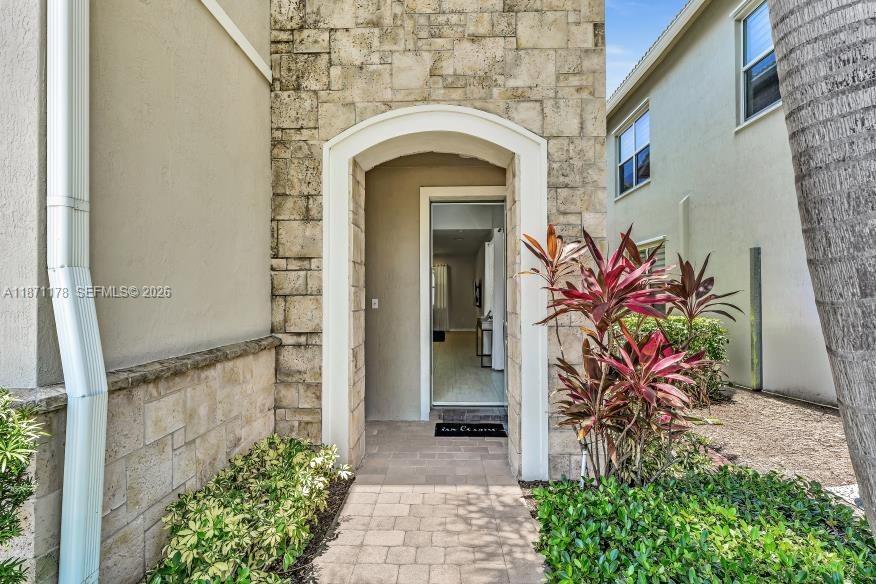 A stone-accented entryway leads to an open doorway revealing a view into the home's interior — 4353 Large Leaf Ln, Hollywood FL 33021, HOLLYWOOD, FL