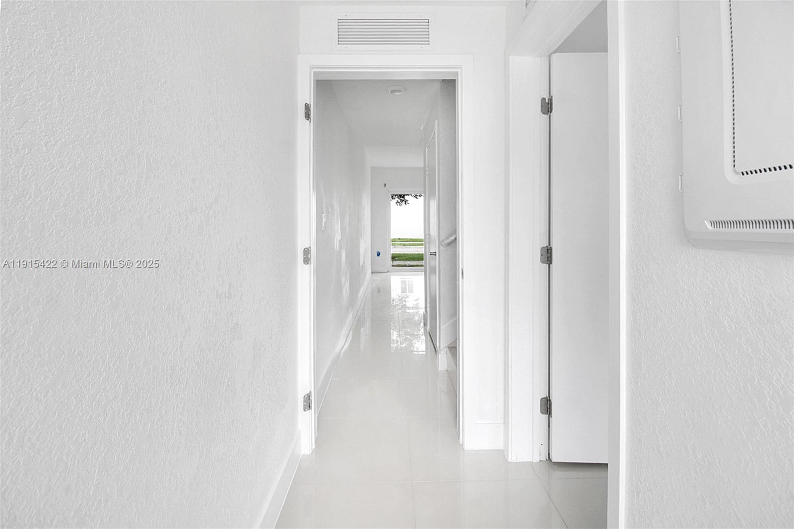 A bright white hallway leads to a doorway with a view of green grass outside — 14482 SW 259th St, Homestead FL 33032, HOMESTEAD, FL