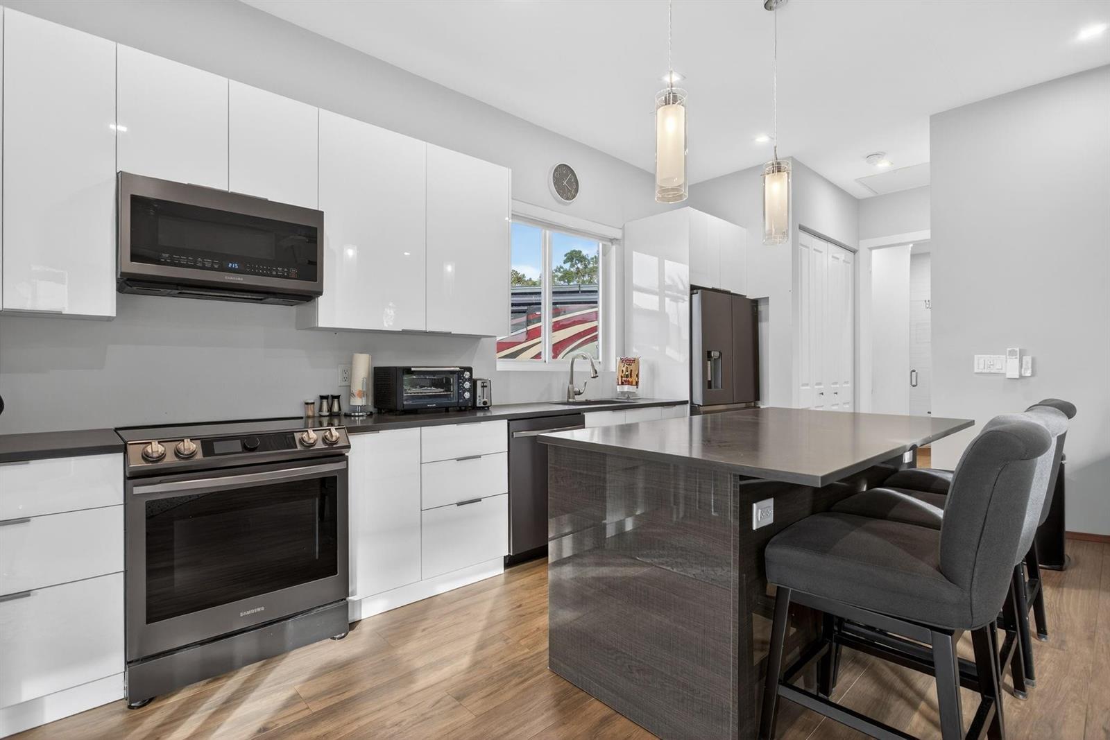 A modern kitchen features white cabinets, dark countertops, a kitchen island, and stainless steel appliances — 119 S Cortez Drive # 119, Margate FL 33068, MARGATE, FL
