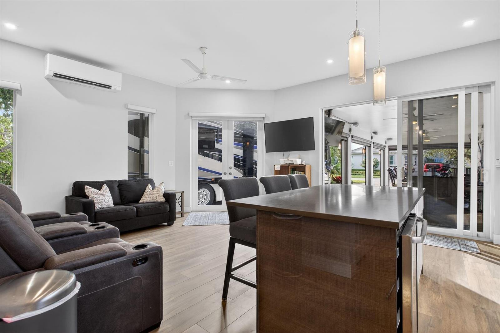 A living room and kitchen area features dark furniture, wood-look flooring, and a large RV outside — 119 S Cortez Drive # 119, Margate FL 33068, MARGATE, FL