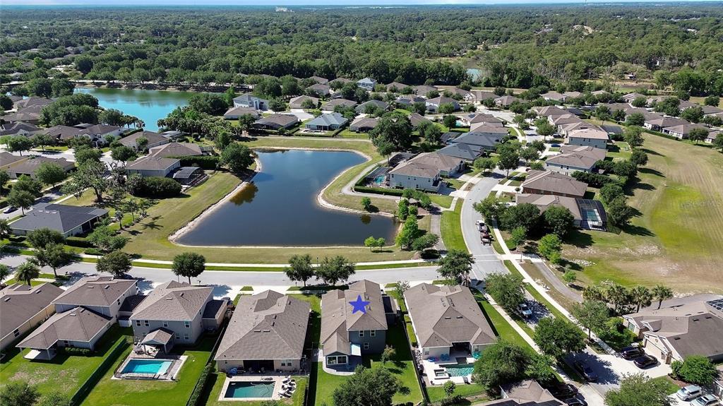 An aerial view shows a suburban neighborhood with houses, a pond, and a blue star — 337 ORCHARD HILL STREET, DELAND, FL