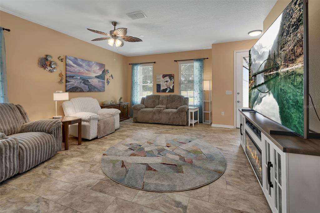 A living room features tile flooring, a large television, a ceiling fan, and multiple sofas — 337 ORCHARD HILL STREET, DELAND, FL