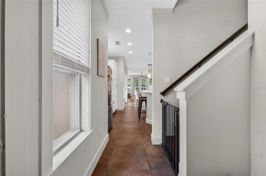A hallway with tile flooring leads from a staircase toward a kitchen and dining area — 1071 ARAGON AVENUE, WINTER PARK, FL