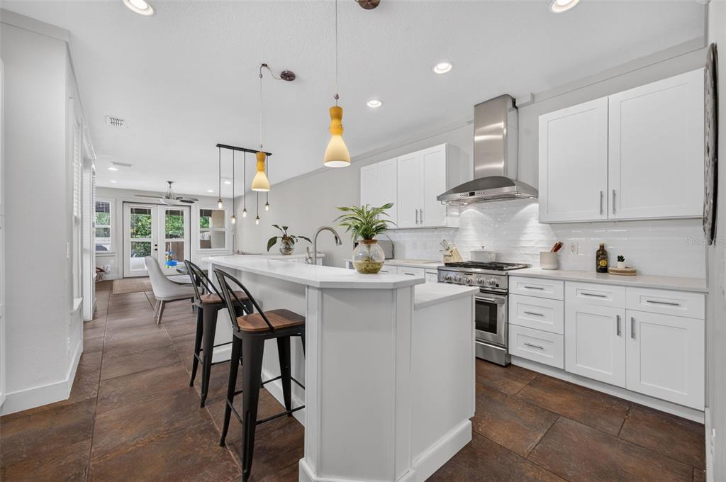 A modern kitchen features white cabinetry, a large island with bar seating, and tile flooring — 1071 ARAGON AVENUE, WINTER PARK, FL