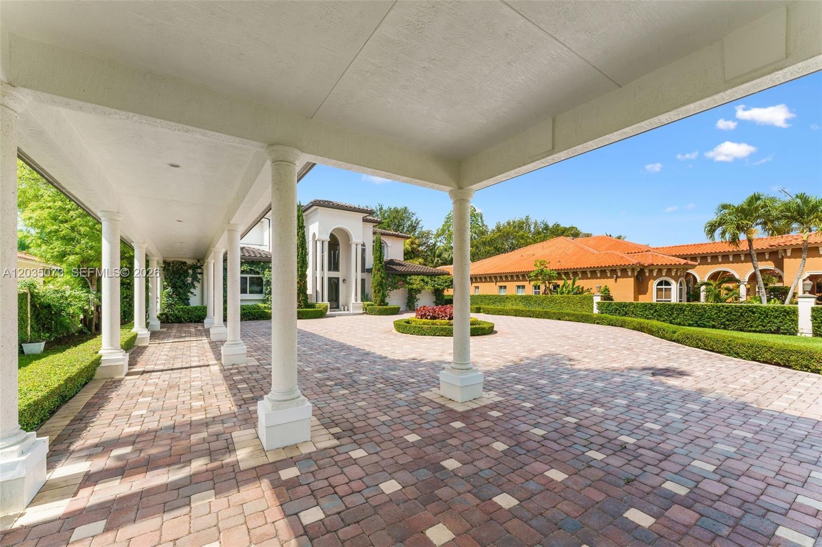 A covered walkway with white columns leads to a paved driveway in front of a house — 13470 SW 32nd St, Miami FL 33175, MIAMI, FL