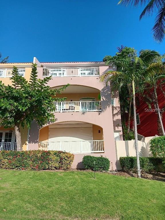 A multi-story peach-colored building features arched balconies, white railings, and a manicured lawn — LAS CASITAS VILLAGE 1 1 AVE CONQUISTADOR UNIT 5393, FAJARDO, PR