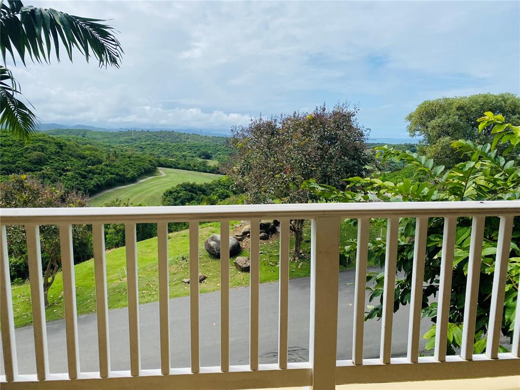 A view from a balcony overlooking a golf course, trees, and distant hills — LAS CASITAS VILLAGE 1 1 AVE CONQUISTADOR UNIT 5393, FAJARDO, PR