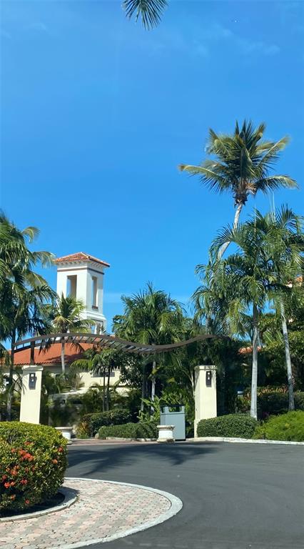 A paved driveway leads to a gated entrance with palm trees and a white tower — LAS CASITAS VILLAGE 1 1 AVE CONQUISTADOR UNIT 5393, FAJARDO, PR