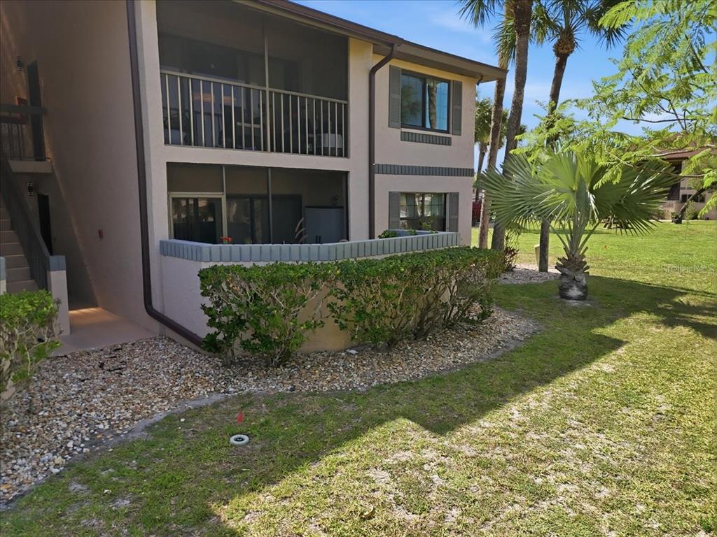 A two-story apartment building features a ground-floor patio with a low wall and landscaping — 19505 QUESADA AVENUE UNIT LL108, PORT CHARLOTTE, FL