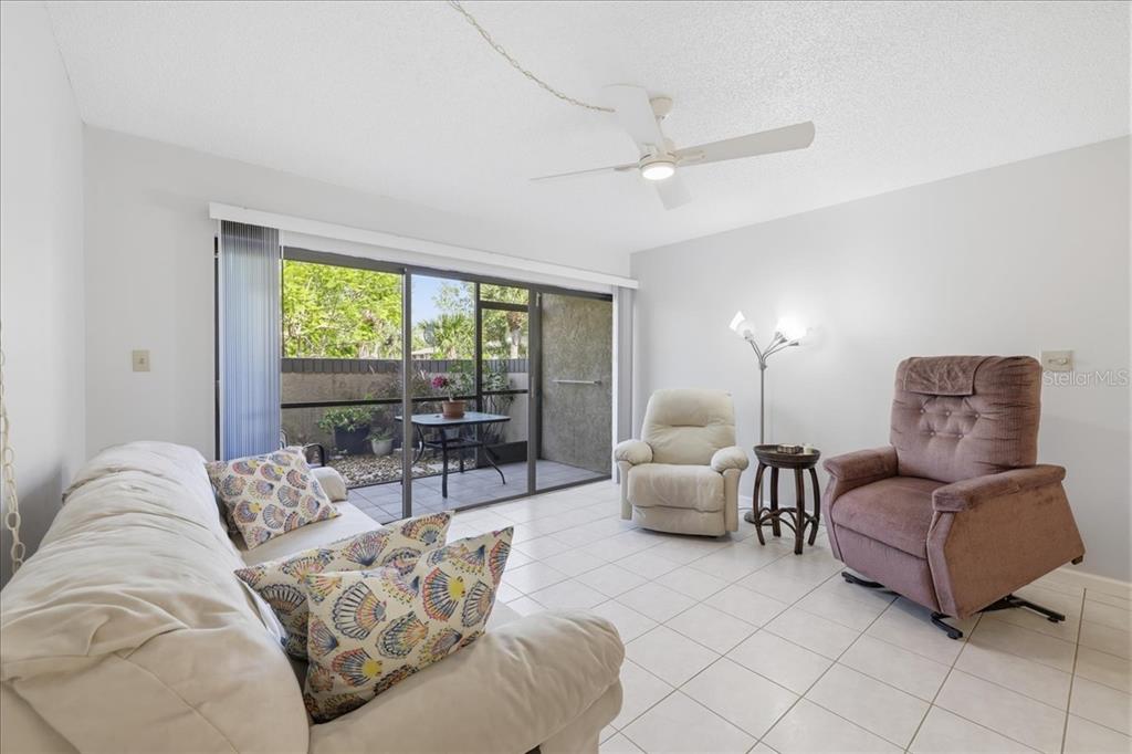 A living room with tile flooring, a ceiling fan, and sliding doors to a patio — 19505 QUESADA AVENUE UNIT LL108, PORT CHARLOTTE, FL