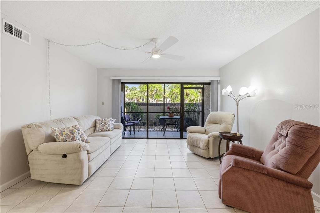 A living room with tile floors, a ceiling fan, and a sliding door to a patio — 19505 QUESADA AVENUE UNIT LL108, PORT CHARLOTTE, FL