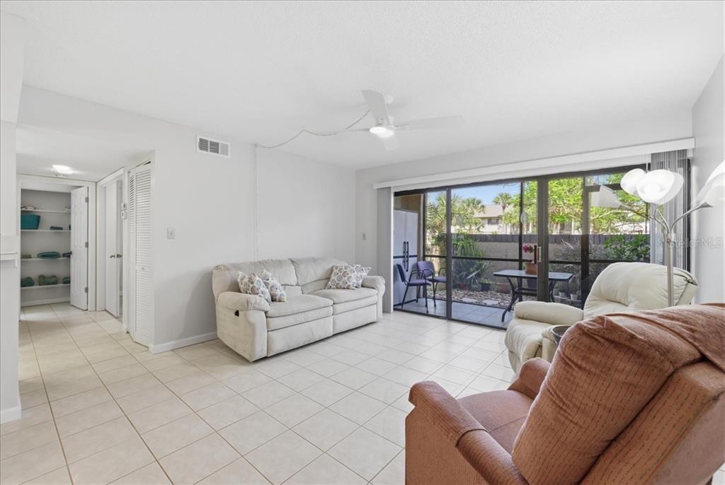 A living room features light tile floors, a beige sofa, a recliner, and sliding glass doors — 19505 QUESADA AVENUE UNIT LL108, PORT CHARLOTTE, FL
