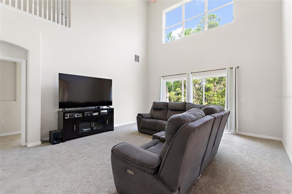 A living room with high ceilings, a large television, and a gray sectional sofa — 4039 NAVIGATOR WAY, KISSIMMEE, FL