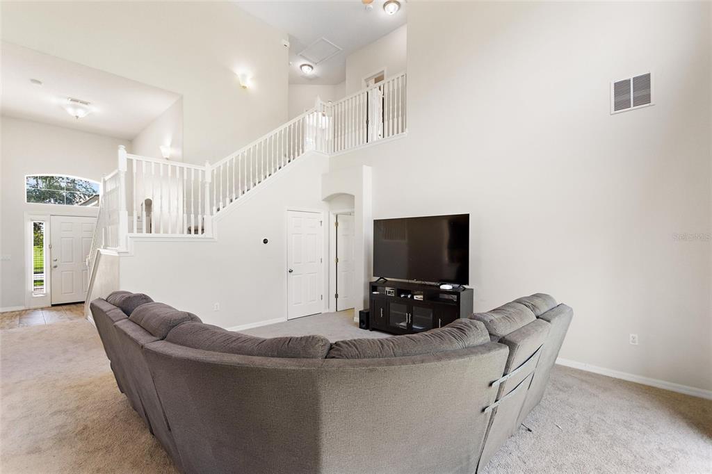 A living room features a large sectional sofa, a television on a stand, and stairs — 4039 NAVIGATOR WAY, KISSIMMEE, FL