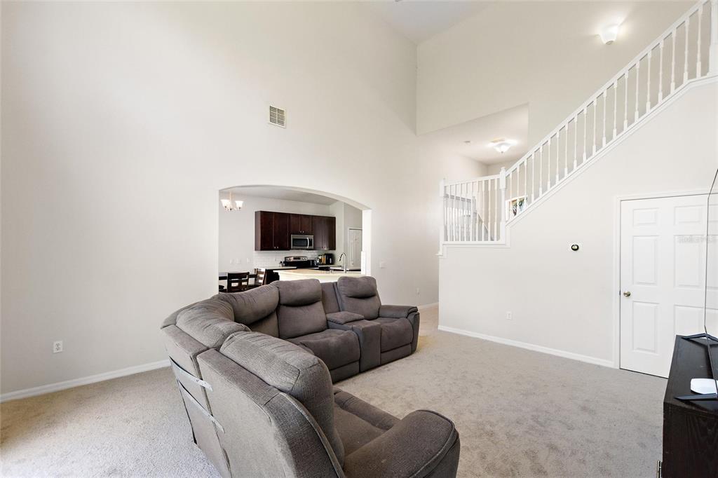 A living room with a gray sectional sofa, high ceilings, and a staircase — 4039 NAVIGATOR WAY, KISSIMMEE, FL